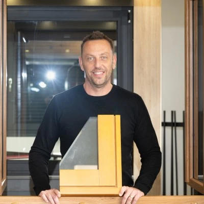 Portrait professionnel d'un menuisier ou responsable d'équipe de J'écoRénove en tenue de travail appropriée, dans l'atelier ou sur un chantier de pose, engagé en conversation avec un client ou écoutant attentivement ses besoins, illustrant l'écoute, le conseil personnalisé et l'assistance qui caractérisent la philosophie de l'entreprise.