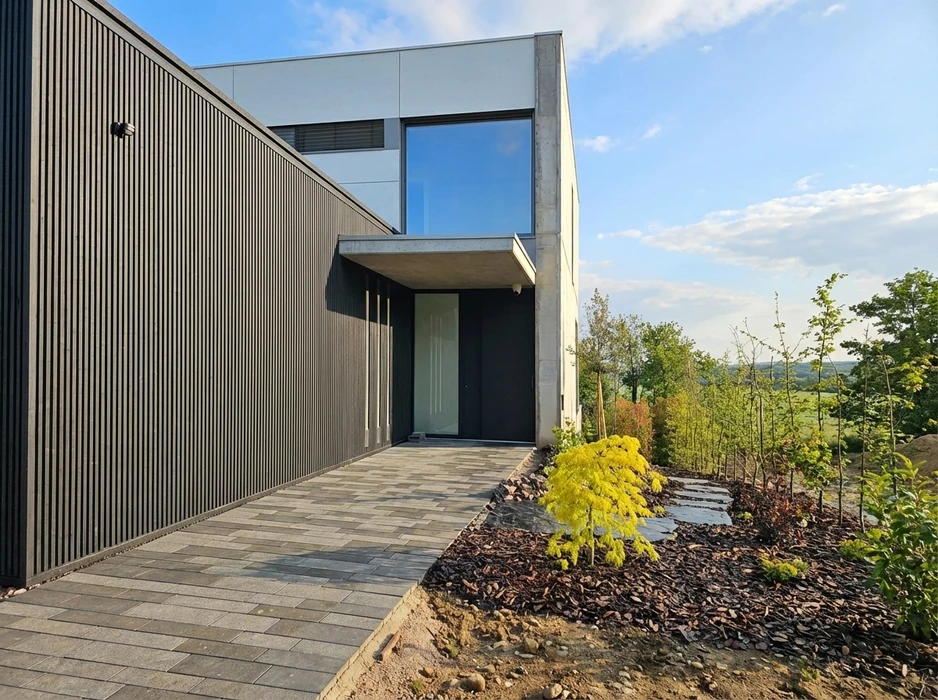 Maison individuelle de plain-pied en briques rouges avec extension à pignon, équipée de panneaux photovoltaïques en toiture
