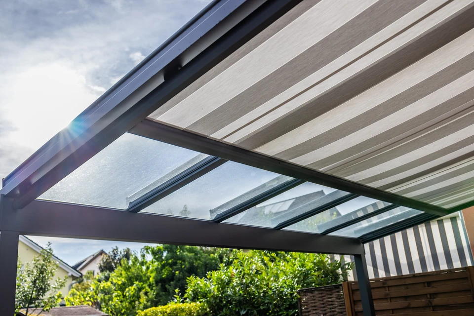 Un artisan en casquette rouge et t-shirt gris travaille sur une structure de pergola en bois