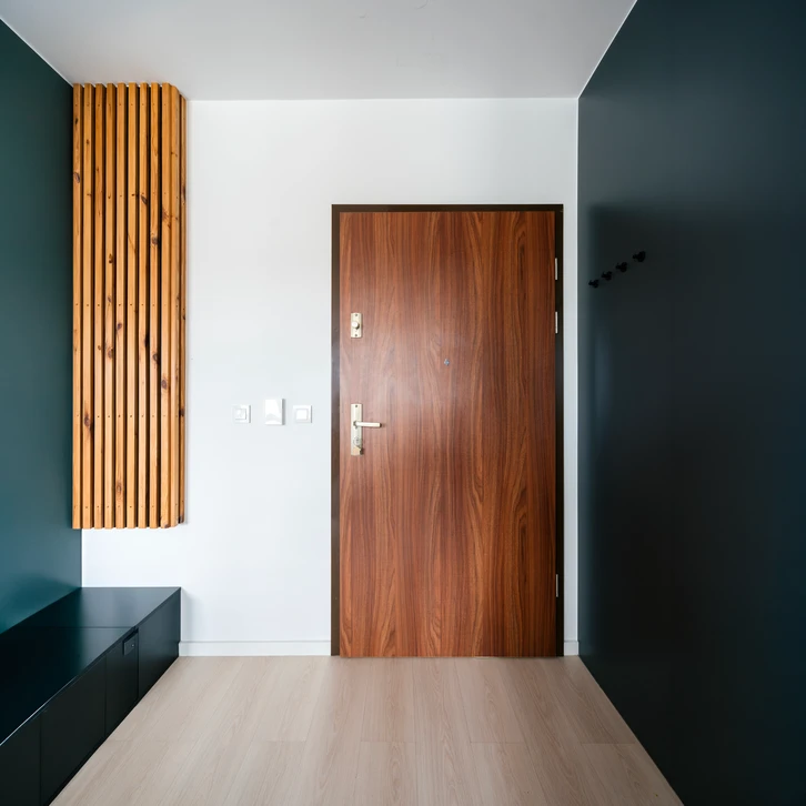 Un technicien en uniforme bleu installe ou ajuste une porte intérieure en bois naturel