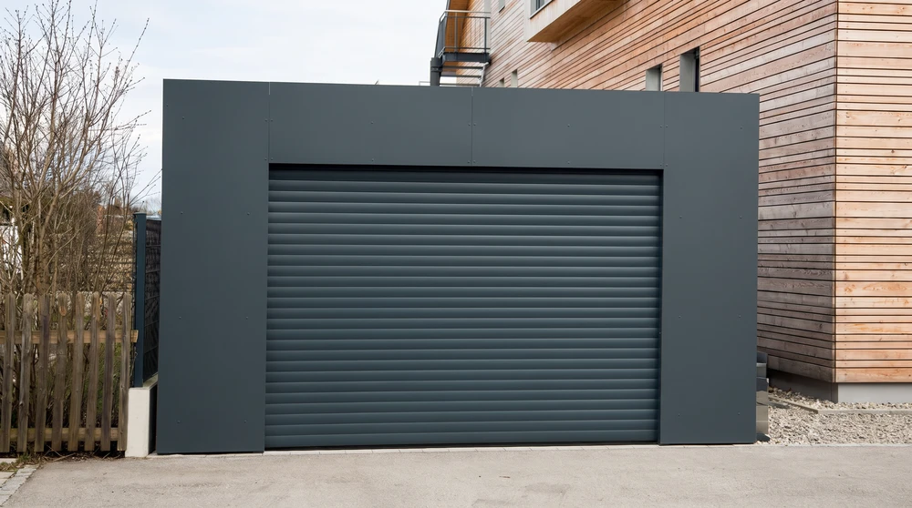 Façade extérieure d'une maison méditerranéenne avec une fenêtre équipée d'un volet roulant aluminium blanc partiellement descendu et de volets battants aluminium gris-bleu ouverts