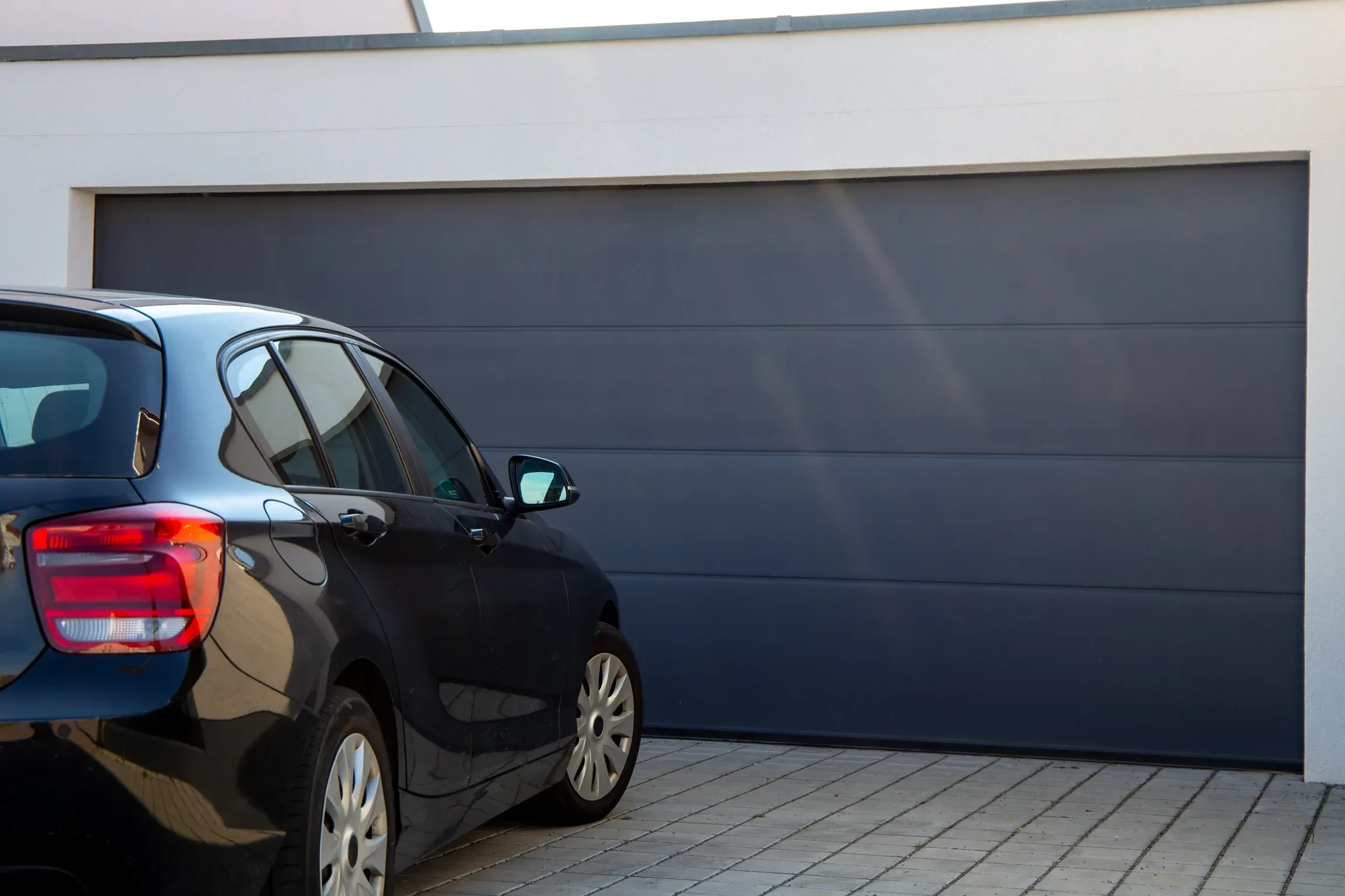 Maison contemporaine à étages avec façade blanche et toiture grise, garage intégré à porte sectionnelle anthracite