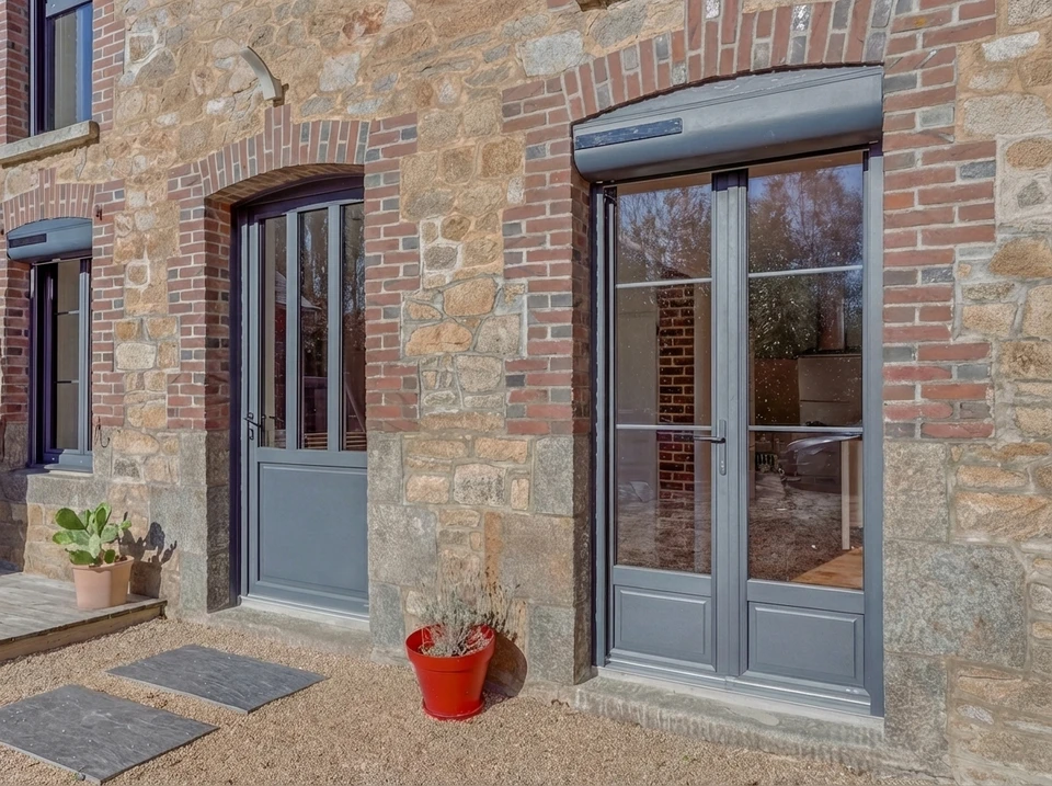 Terrasse extérieure d'une maison en briques rouges avec mobilier de jardin aluminium blanc/taupe (table et chaises à assise textilène)